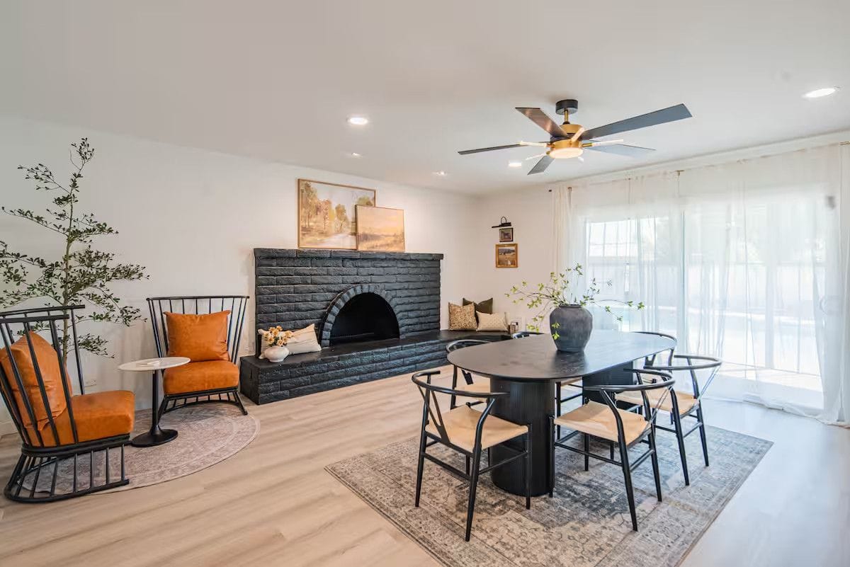 Dining room after a turnover: oval table and chairs wiped down, cleared fireplace hearth, vacuumed rug