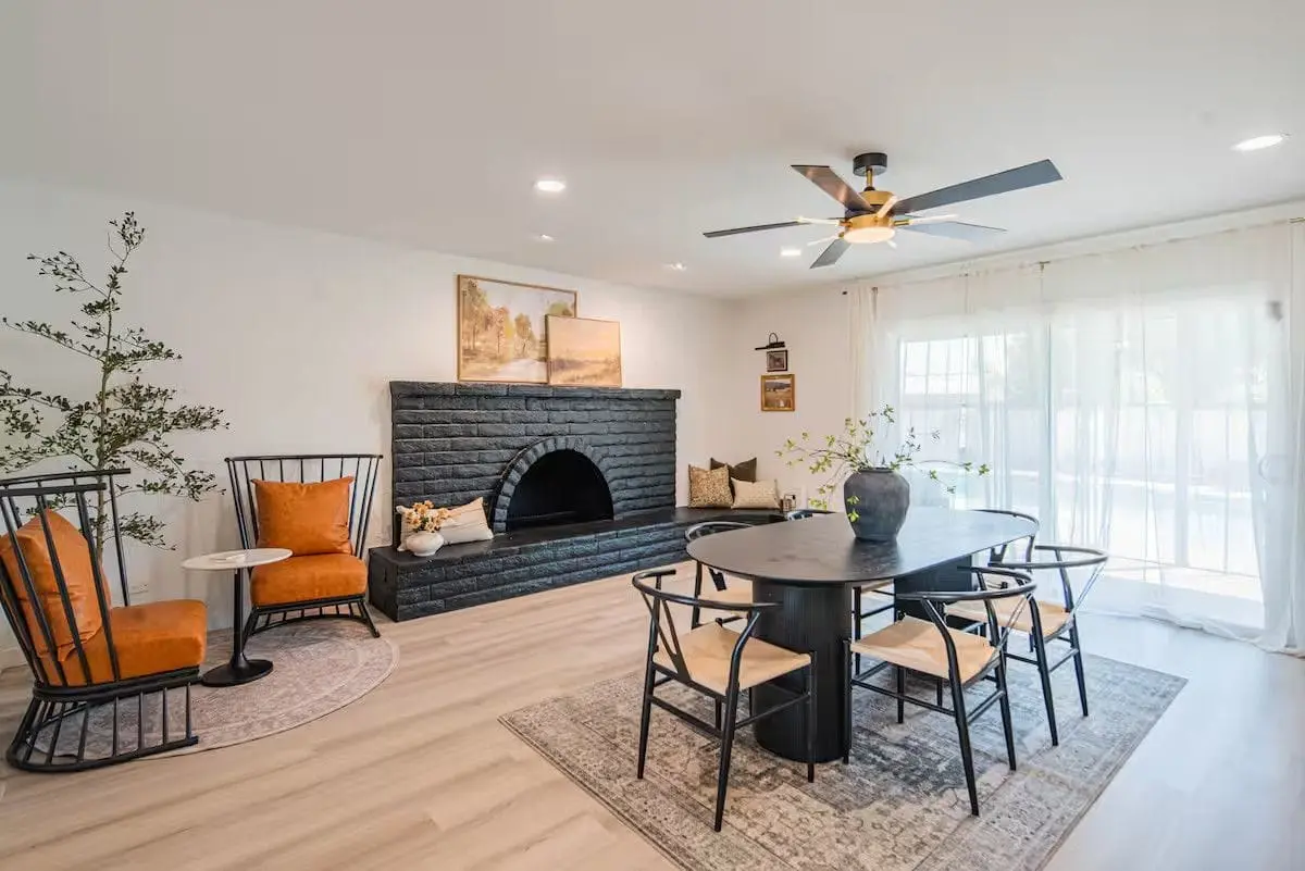 Dining room after a turnover: oval table and chairs wiped down, cleared fireplace hearth, vacuumed rug